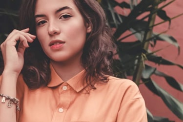 woman in orange shirt with hand stroking her hair